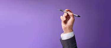 Eine Hand, die einen Stift hochhält. Symbolisch für die Stärkung des Bewerbungsprozesses.