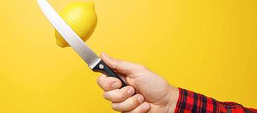 Handwerk und sozialer Mehrwert Eine Hand hält ein Messer um eine Zitrone zu schneiden