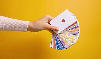 Eine Hand hält einen Faecher Karten. Symbolisch für die Auswahl an Bereichen, die Coaching angeschaut werden