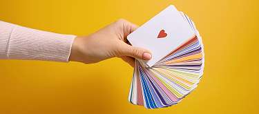 Individuelles Coaching Foerderprogramm Eine Hand hält einen Faecher Karten. Symbolisch für die Auswahl an Bereichen, die Coaching angeschaut werden