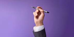 Eine Hand hält einen Kugelschreiber hoch. Ein Schreibtool für die Bewerbung