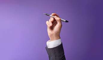 Eine Hand hält einen Kugelschreiber hoch. Ein Schreibtool für die Bewerbung