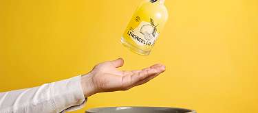 Likör aus geretteten Lebensmitteln Eine Hand fängt einen Limoncello, bestehend aus Zitronen die sonst zu Food Waste geworden wäre.