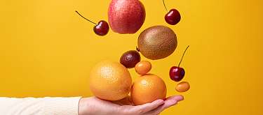 Mehr Früchte für mehr Geschmack Eine Hand fängt Früchte, die herab fallen. Und symbolisiert damit Food Save.
