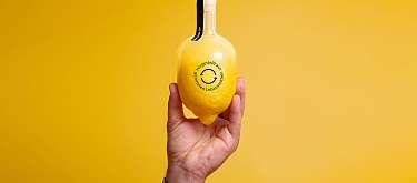 Handgemacht aus geretteten Lebensmitteln eine Zitrone wird im oberen Teil zur Limoncelloflasche. Die Zitrone ist gekennzeichnet mit dem Label Food Save: Produkt hergestellt aus geretteten Lebensmitteln