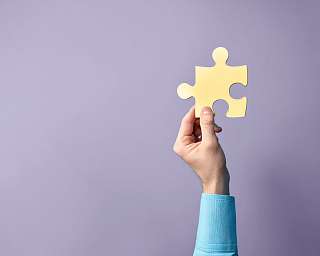 Eine Hand hält ein Puzzleteil hoch