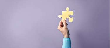 Eine Hand die eine Puzzle-Teil hochhält als Symbol für Arbeitsintegration